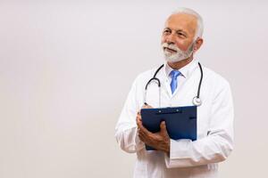 Portrait of  senior doctor writing notes  on  gray background. photo