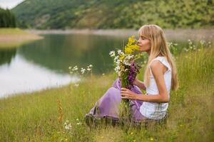 Woman smelling flowers while spending time in the beautiful nature. photo