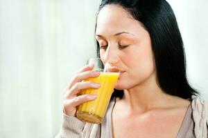 joven mujer Bebiendo Fresco naranja jugo foto