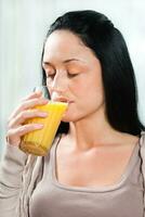 Young woman drinking fresh orange juice photo