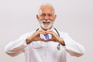 Portrait of senior doctor showing heart shape with hands on gray background. photo