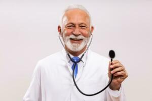 Portrait of  senior doctor holding  stethoscope on gray background. photo