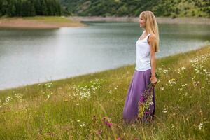 Woman holding bouquet of flowers and enjoys in the beautiful nature photo