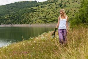 Woman holding bouquet of flowers and walking in the beautiful nature. photo