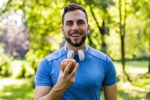 Sporty man eating apple in the park. photo