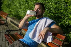 Handsome man drinking water and resting after exercise in the park. photo