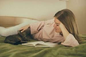 Beautiful woman reading book and spending time with her cat.Toned image. photo