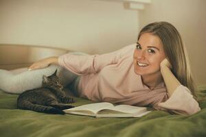 Beautiful woman reading book and spending time with her cat.Toned image. photo