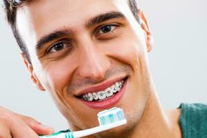 Man with braces brushing his teeth photo