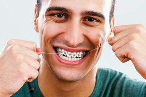 hombre con tirantes limpieza su dientes con dental seda floja foto