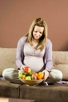 embarazada joven mujer comiendo Fruta foto