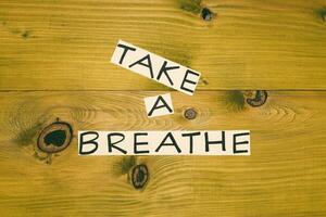 Photo of text take a breath on wooden table.Toned image.