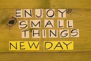 Image of text enjoy small things and new day on wooden table.Toned photo. photo