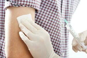 Close up image of doctor giving  getting an injection in the arm photo