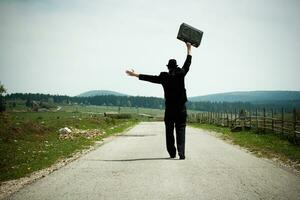 Man holding a suitcase on a road photo