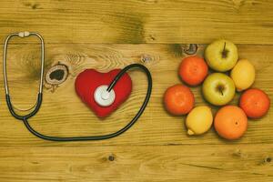 imagen de fruta, estetoscopio y corazón forma en de madera mesa.tonificada foto. foto