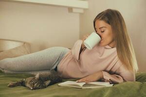 hermosa mujer leyendo libro, bebiendo café y gasto hora con su gato.tonado imagen. foto