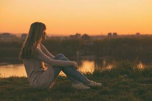 Woman enjoys relaxing and looking at the sunset over the city. photo