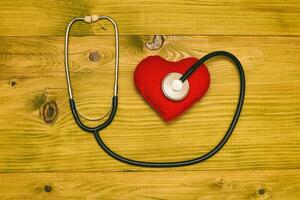 Image of heart shape and stethoscope on wooden table.Toned photo. photo