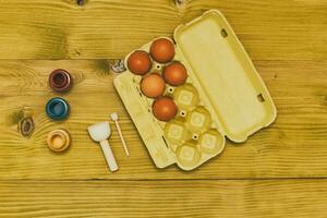 huevos en un caja y colores para pintura en de madera mesa.tonificada foto. foto