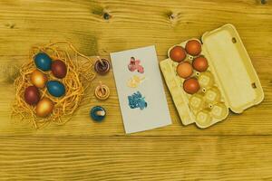 Painted Easter eggs in straw,eggs and colors for painting on wooden table.Toned photo. photo