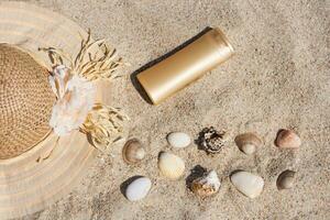 Hat, suntan lotion and sea shells  on the sand photo