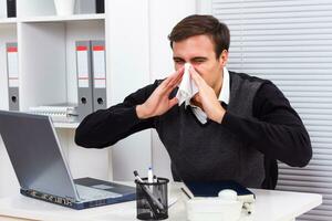 Businessman having flu while working photo