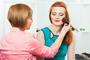 Make up artist applying  make up on a beautiful woman photo