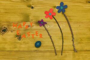 Happy Easter message with painted  eggs  and flowers on wooden table.Toned photo. photo