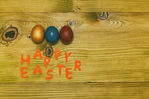 Happy Easter message with painted  eggs  on wooden table.Toned photo. photo