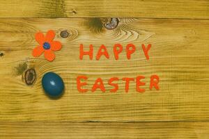 Happy Easter message with painted  egg  and flower on wooden table.Toned photo. photo