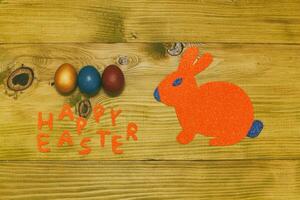 Painted Easter eggs with paper bunny on wooden table.Toned photo. photo