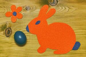 Painted Easter egg with paper bunny on wooden table.Toned photo. photo