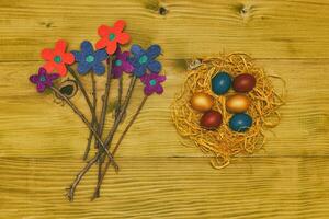 Painted Easter eggs straw with flowers on wooden table.Toned photo