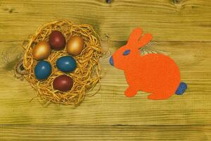 Painted Easter eggs with paper bunny on wooden table.Toned photo. photo