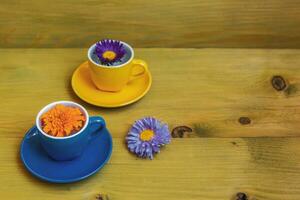 Beautiful flower petals in a cups  on wooden background. photo