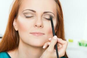 Make up artist applying  make up on a beautiful woman photo