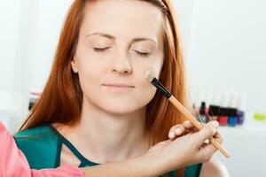 Make up artist applying  make up on a beautiful woman photo