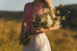 Woman holding bouquet of flowers and enjoys in the nature.Focus on flowers. photo