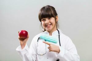Beautiful little doctor showing apple. photo