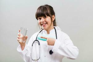 Beautiful little doctor showing glass of water. photo