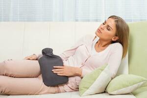 Woman using hot water bottle for stomach cramps photo