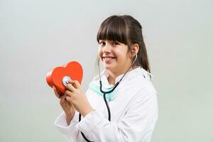 hermosa pequeño cardiólogo participación corazón forma y estetoscopio. foto