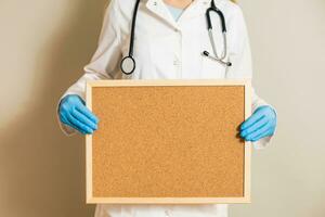 Image of female doctor holding empty corkboard. photo