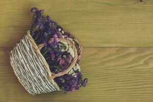 Image of beautiful dried flowers in basket on wooden background. photo