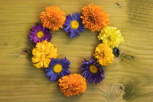 Image of heart shape made with  beautiful flowers on wooden background. photo