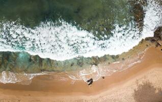 Aerial top view of sandy beach with stunning waves. photo