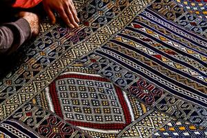 a man sitting on a rug with a colorful pattern photo