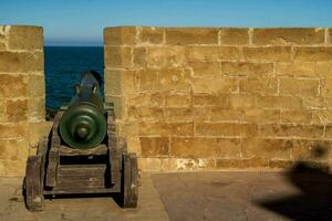 a cannon is sitting on a wall near the ocean photo