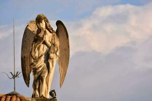 an angel statue on top of a roof with clouds in the background photo